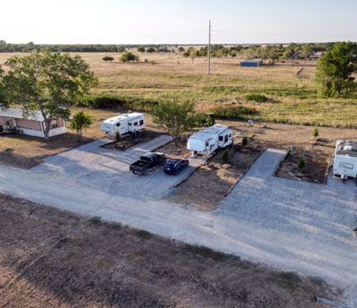 Gravel long-term RV sites with hookups and shade trees at Stoney Acres RV Park